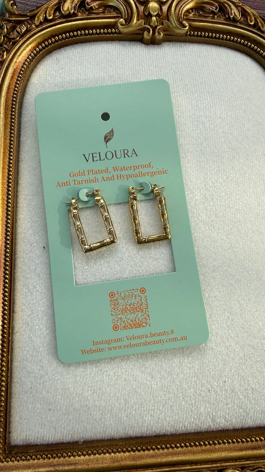 Gold hoop earrings on a Veloura branded card against a white background